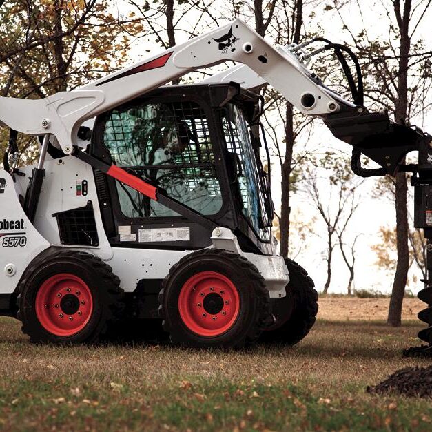 Bobcat skid-steer loader digging a hole with an auger attachment. Bobcat skid-steer loader